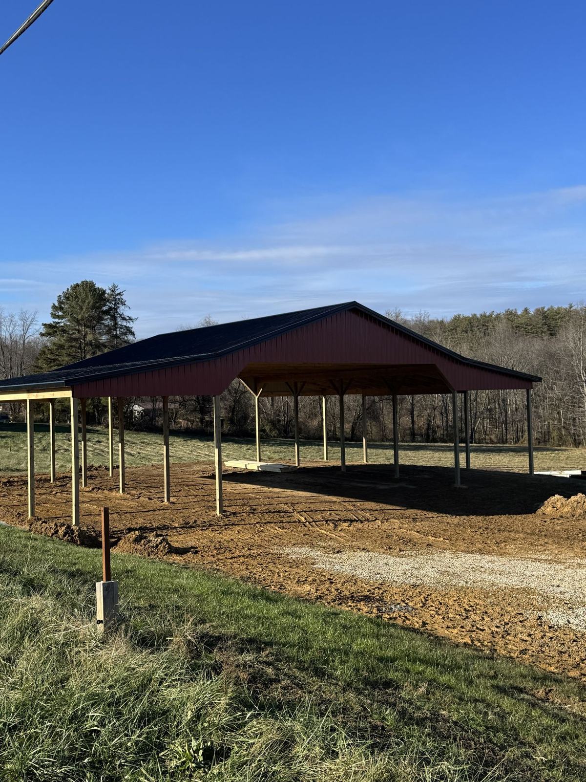 Open red shelter with a black roof on posts