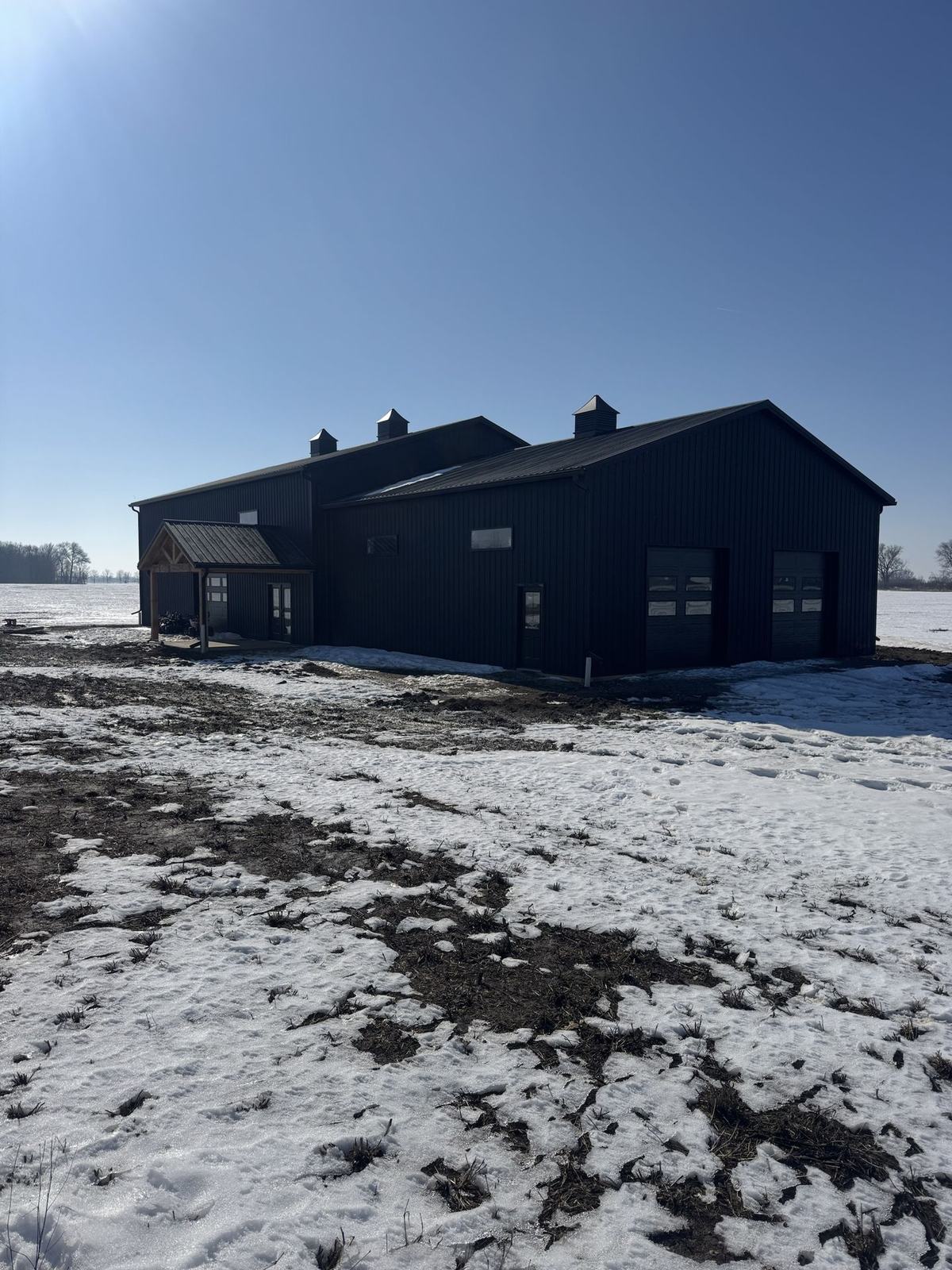 Black shop with overhead doors and cupolas in the snow