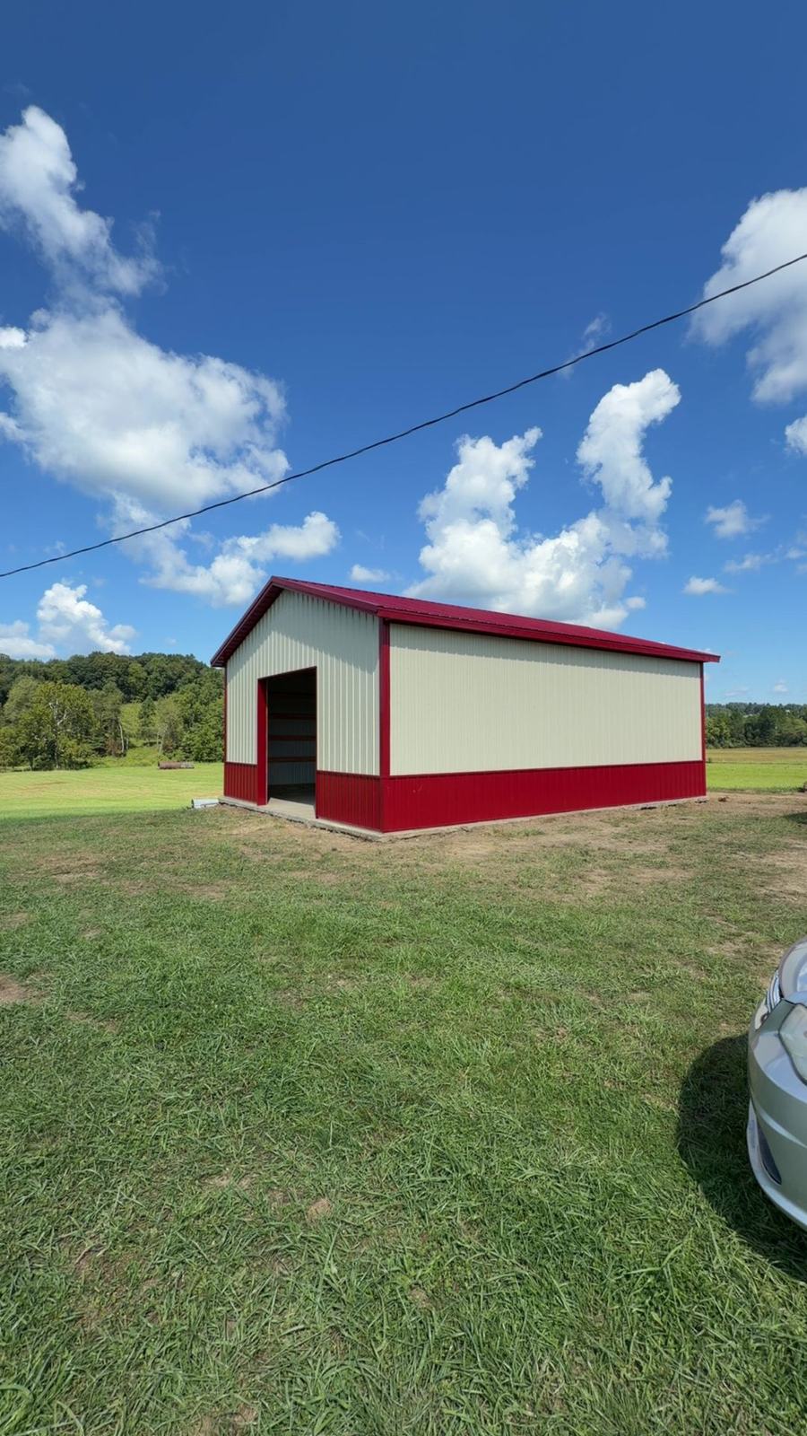 Tan and red garage barn in a grass field